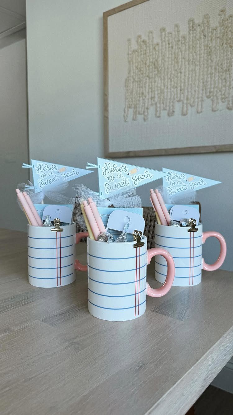 Three striped mugs filled with pencils and gift tags on a wooden table.