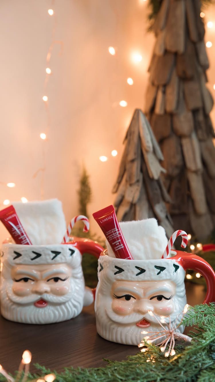 Santa Claus mugs filled with white towels, red lotion, and candy canes.