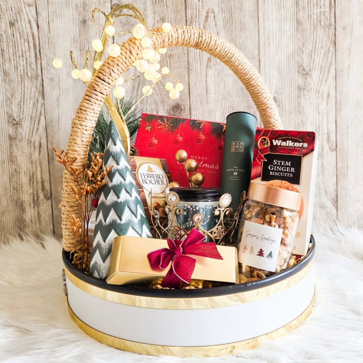 Christmas gift basket with treats, a gold gift box, and a miniature tree.