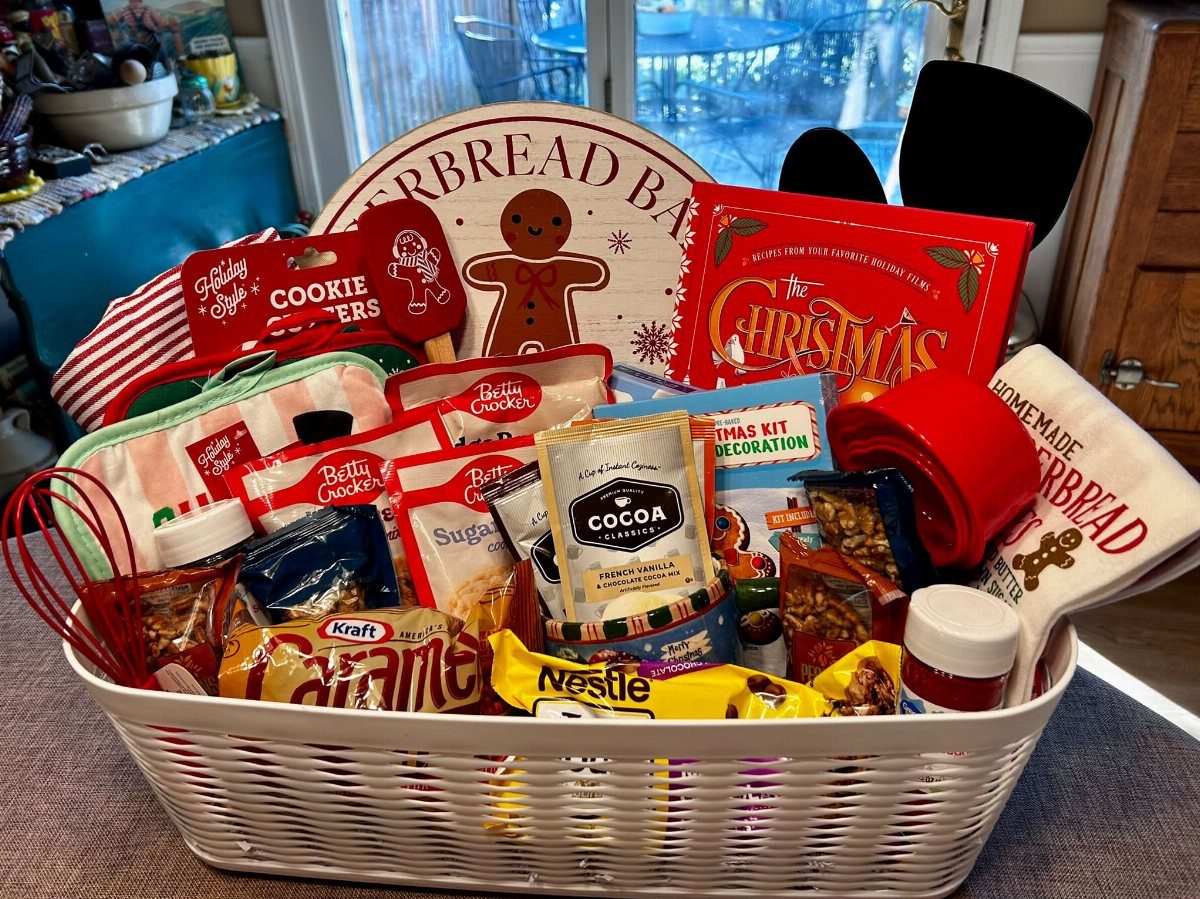 White woven basket filled with cake mixes, cocoa, and baking tools for Christmas.