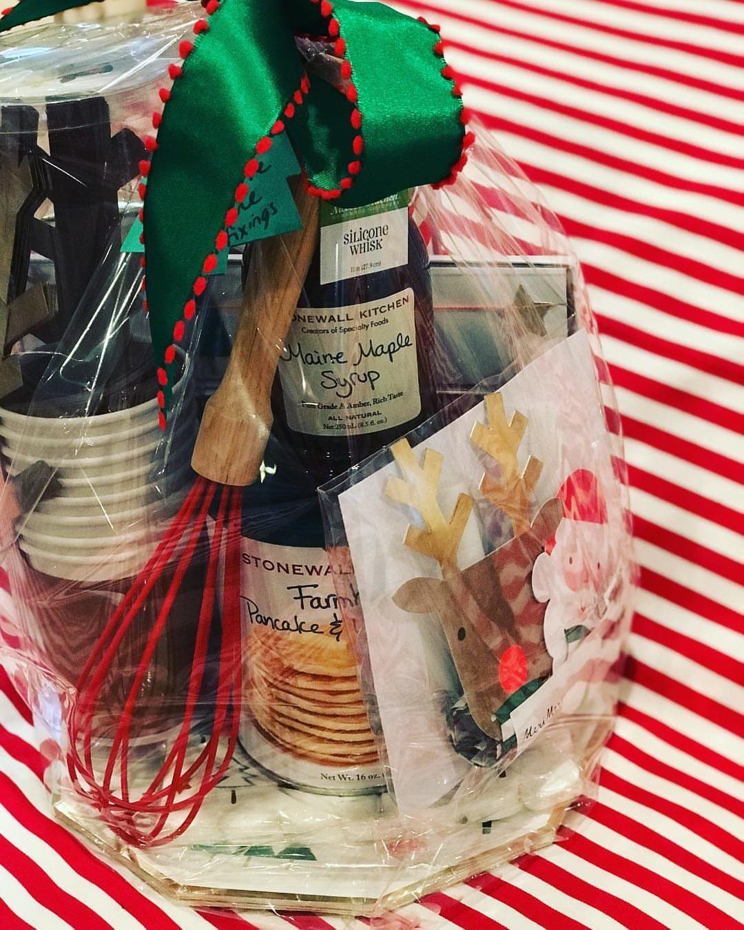 Breakfast gift basket with maple syrup, pancake mix, and red whisk in cellophane.