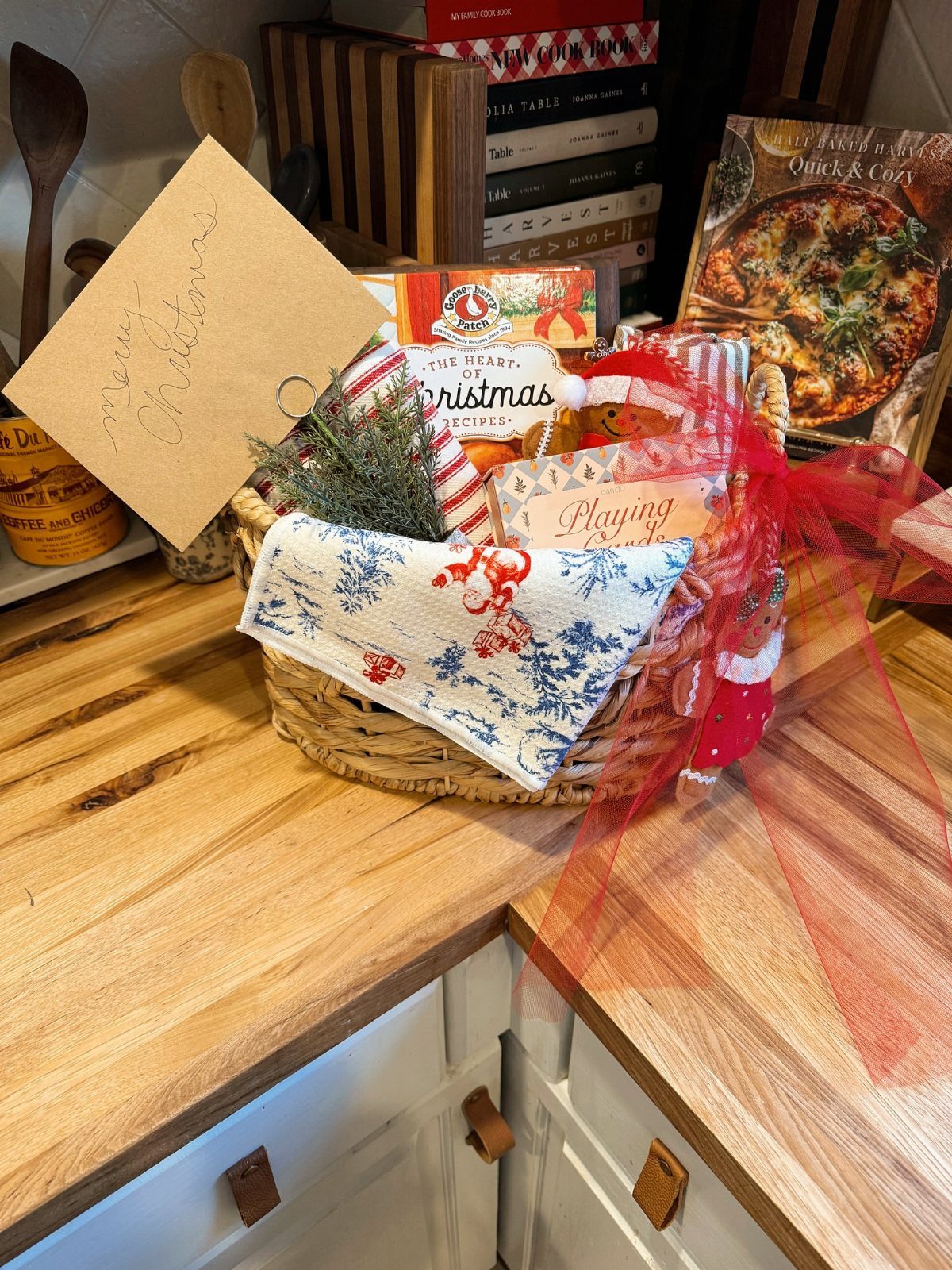 Wicker gift basket with a cookbook, festive red ribbons, and a gift tag.
