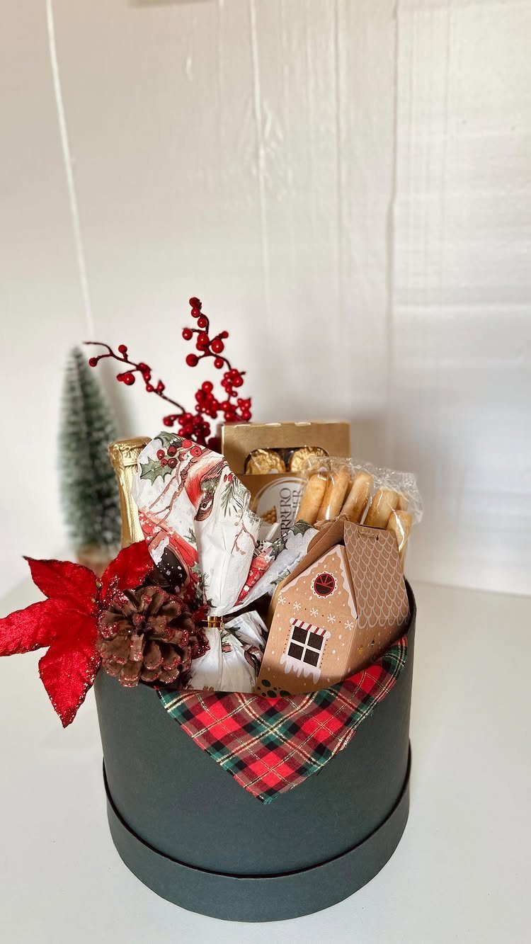 Holiday gift box with sweets, a small house, and festive red decorations.