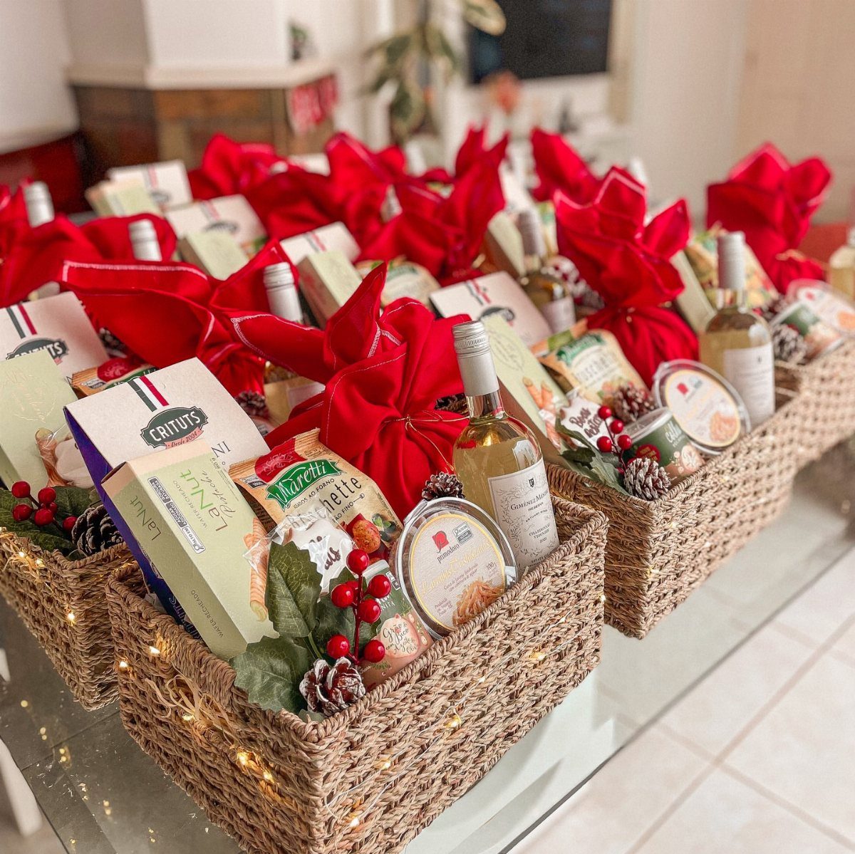 Woven gift baskets filled with gourmet foods and wine, topped with red bows.
