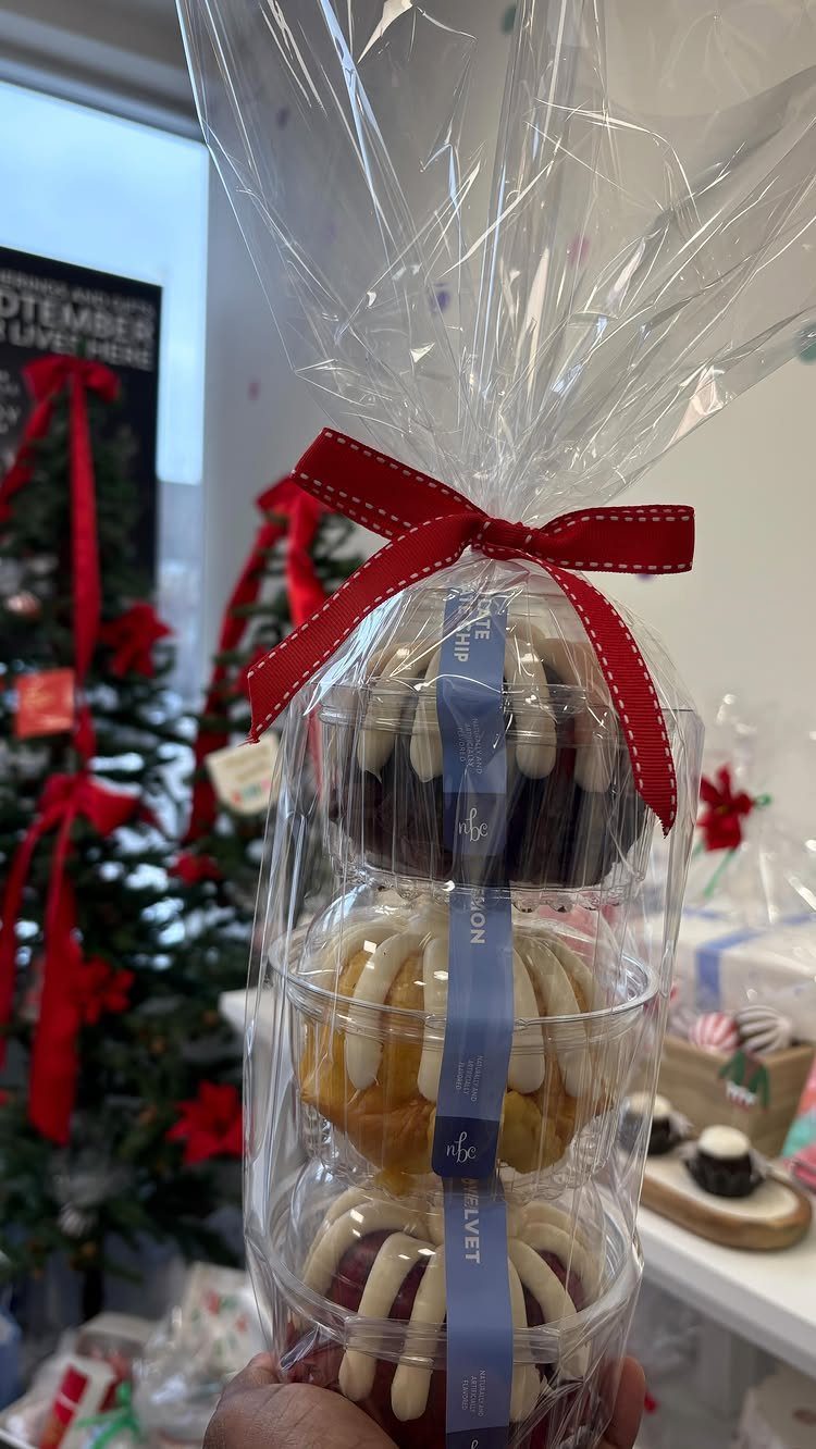 Three tiered cakes in clear packaging wrapped in cellophane with a red bow.