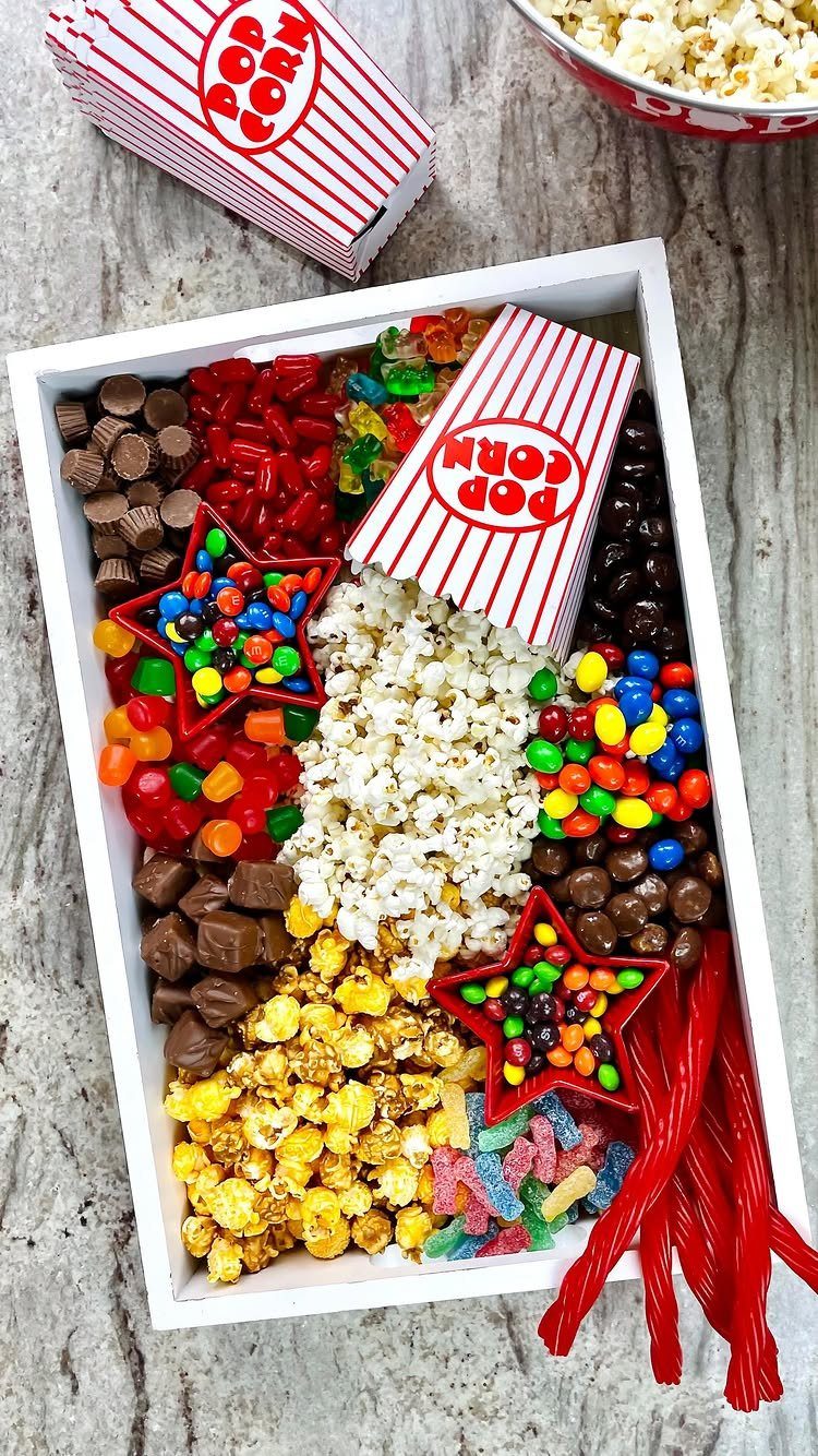 Gift box filled with popcorn, chocolates, and colorful candies for a movie night.