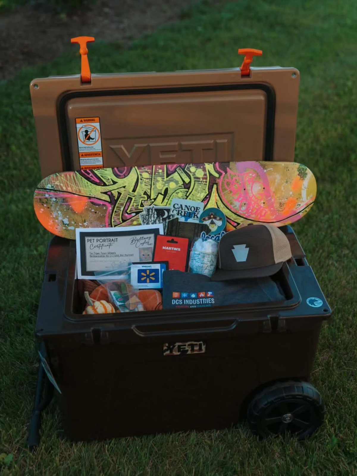 Brown Yeti cooler filled with a skateboard, hat, and gift cards as a raffle prize.