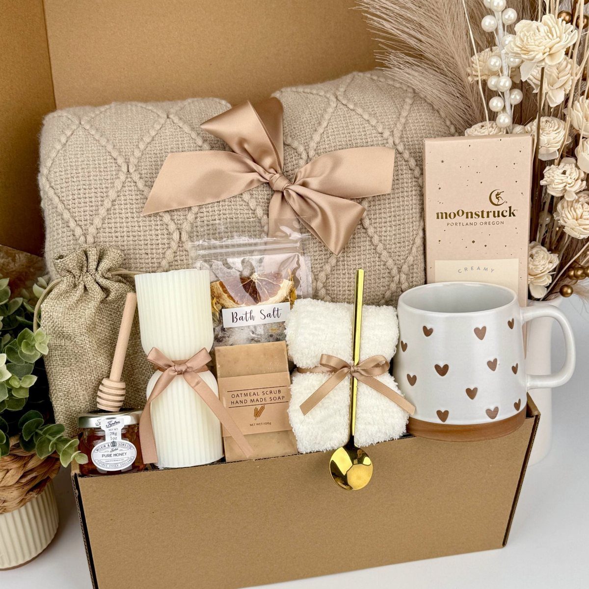 Beige knit blanket and spa accessories arranged in a cardboard gift box.
