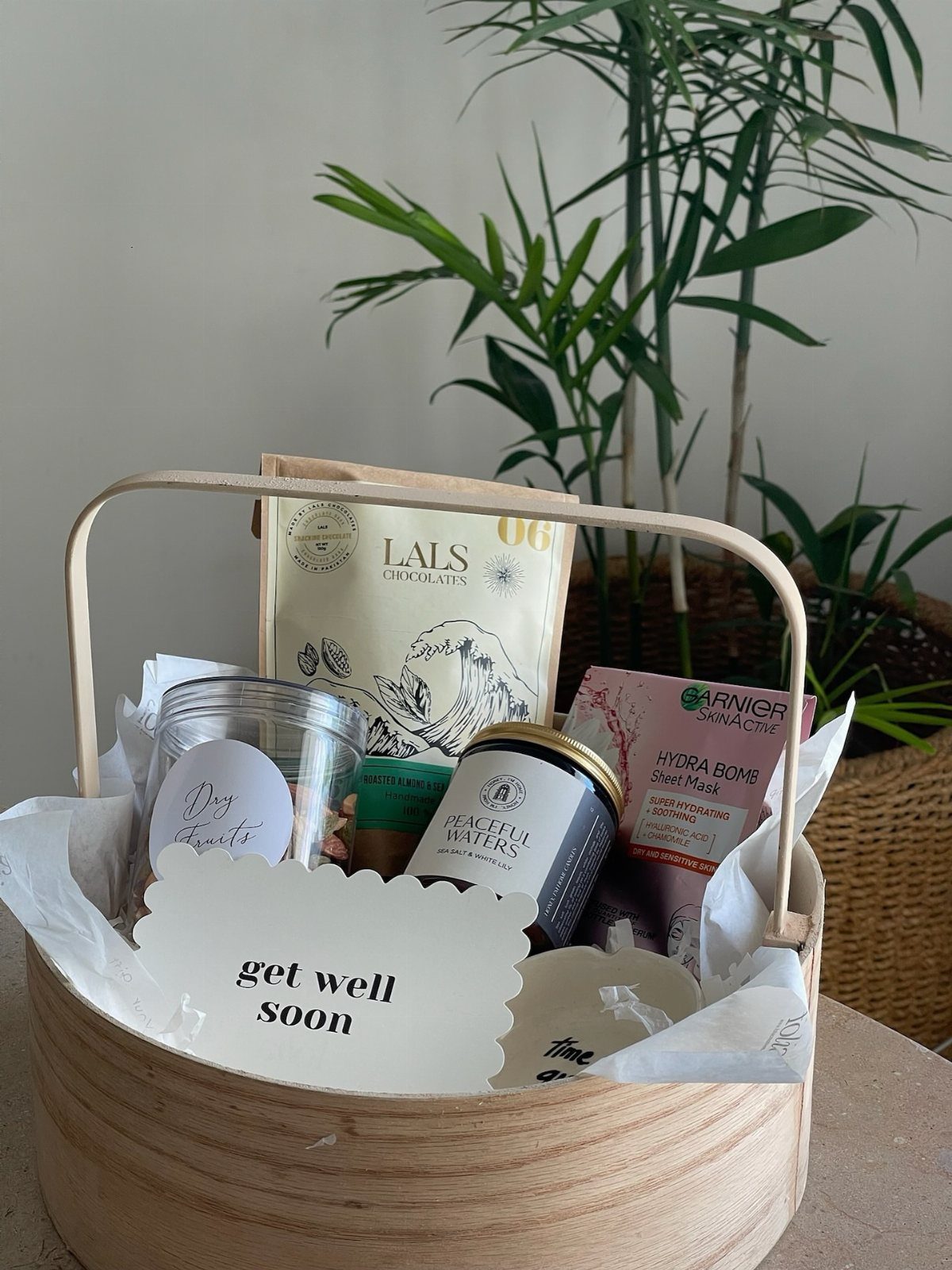 Wooden gift basket with chocolates, a face mask, and a get well soon card.