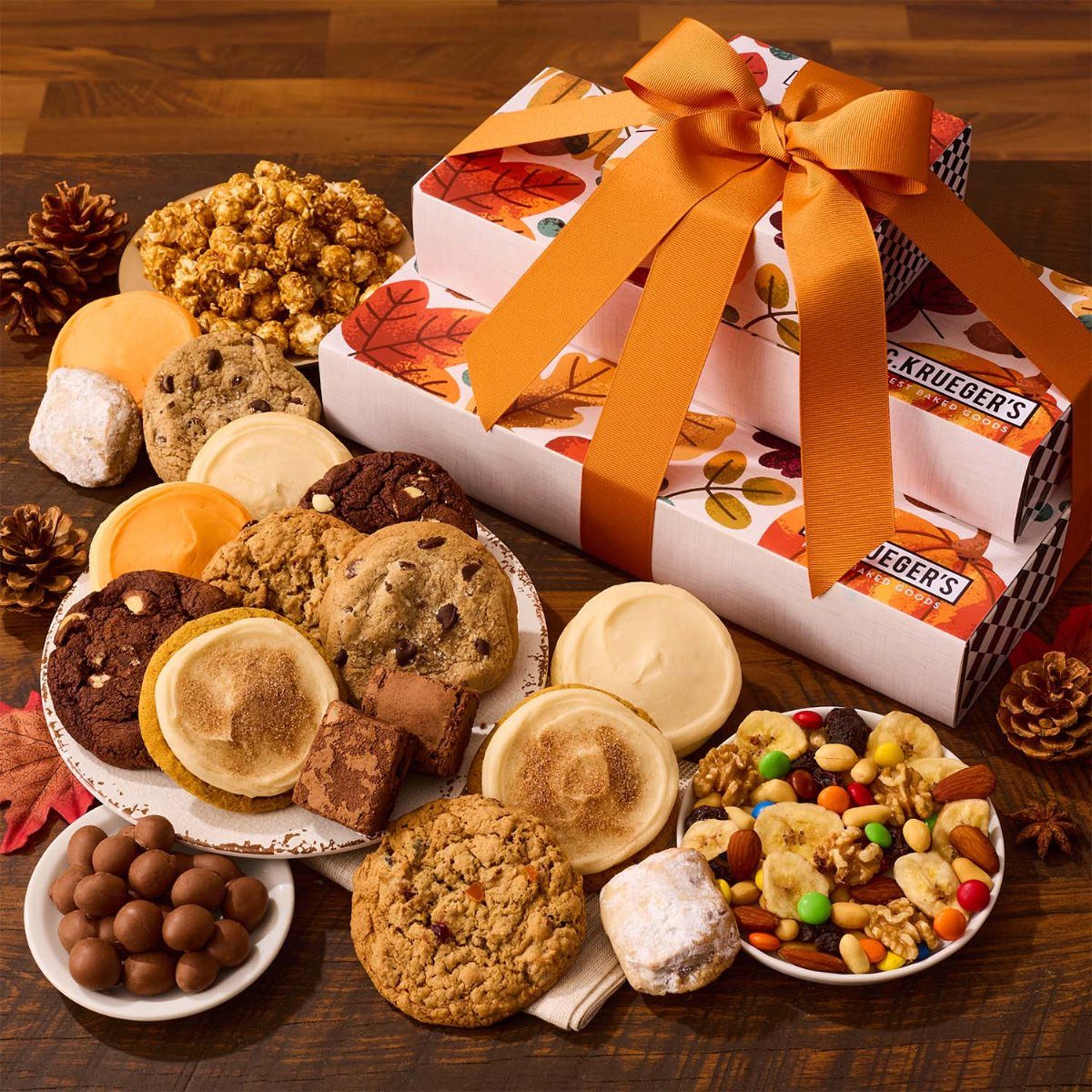 Assorted gourmet cookies and treats next to autumn-themed gift boxes with orange ribbons.