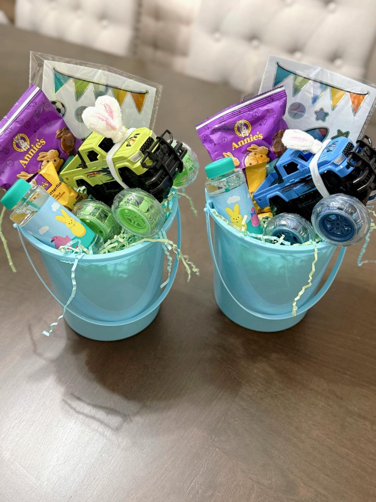 Two blue buckets filled with toy trucks, snacks, and water bottles for Easter.
