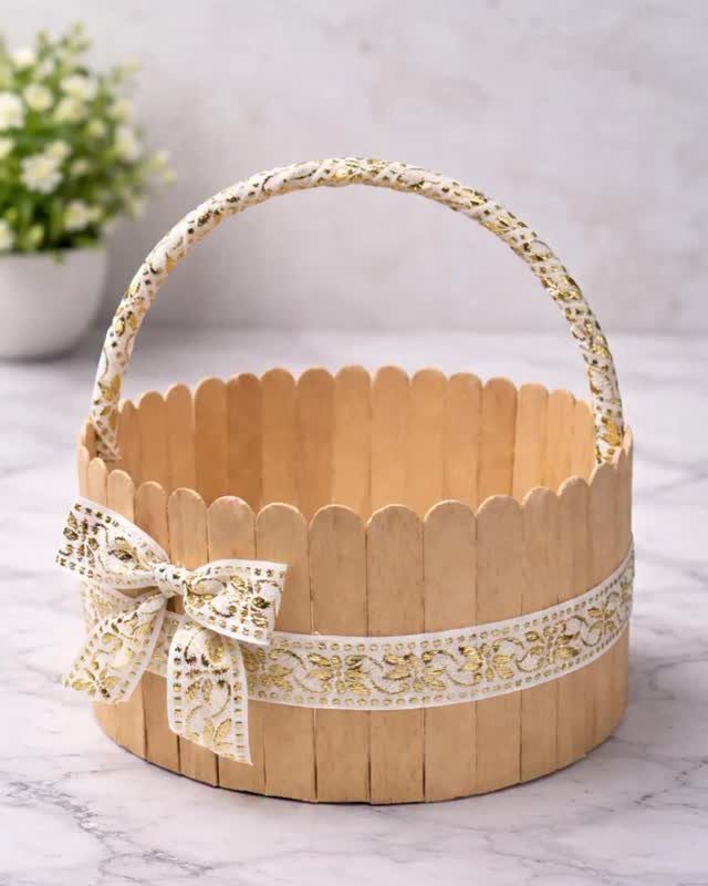 Wooden craft stick basket with a gold patterned ribbon and matching handle.