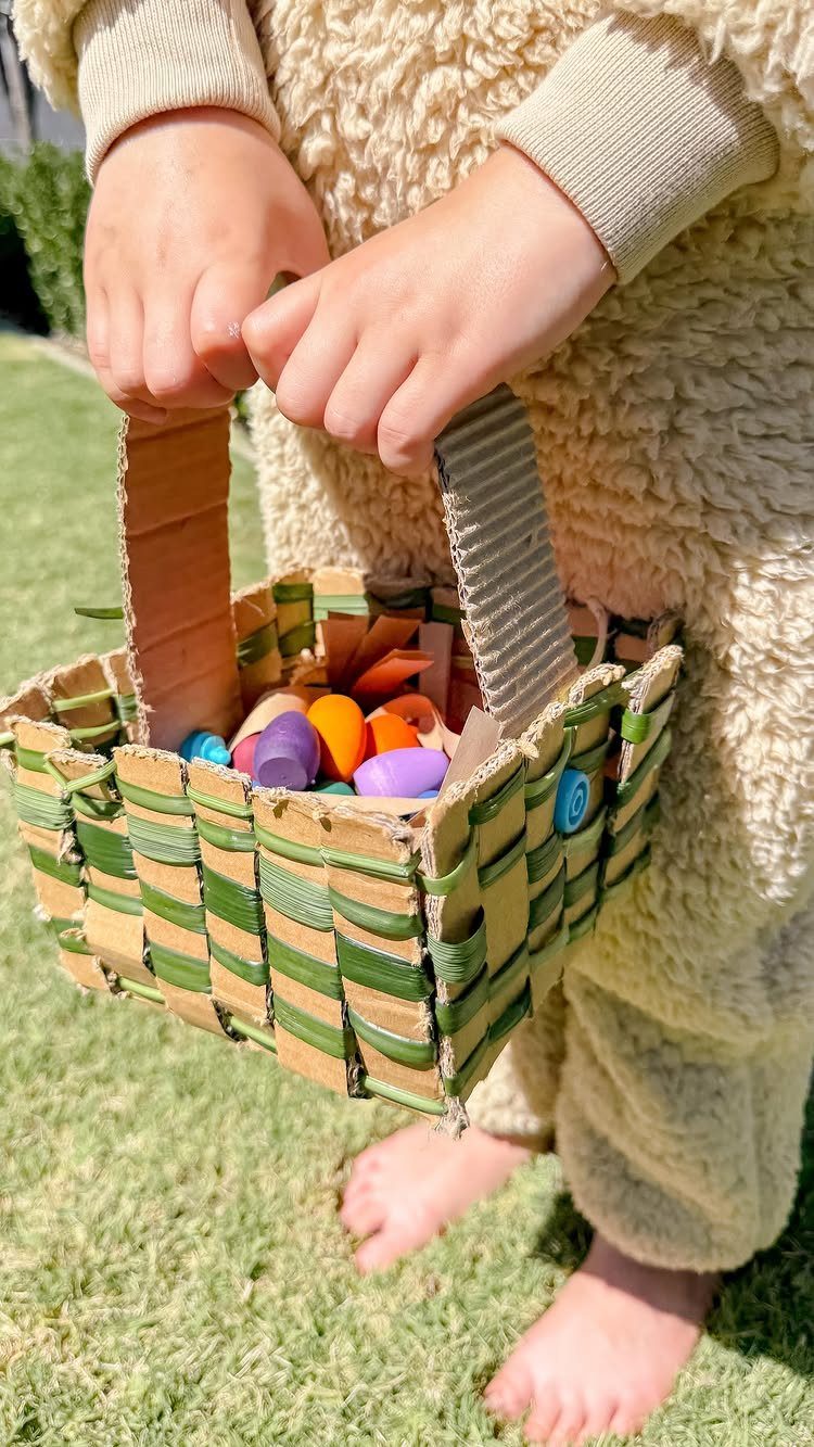 Handmade woven cardboard and paper basket filled with colorful Easter eggs held by child