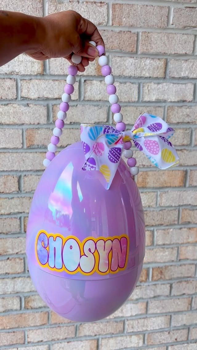 Iridescent purple plastic egg basket with beaded handle and colorful name decal.