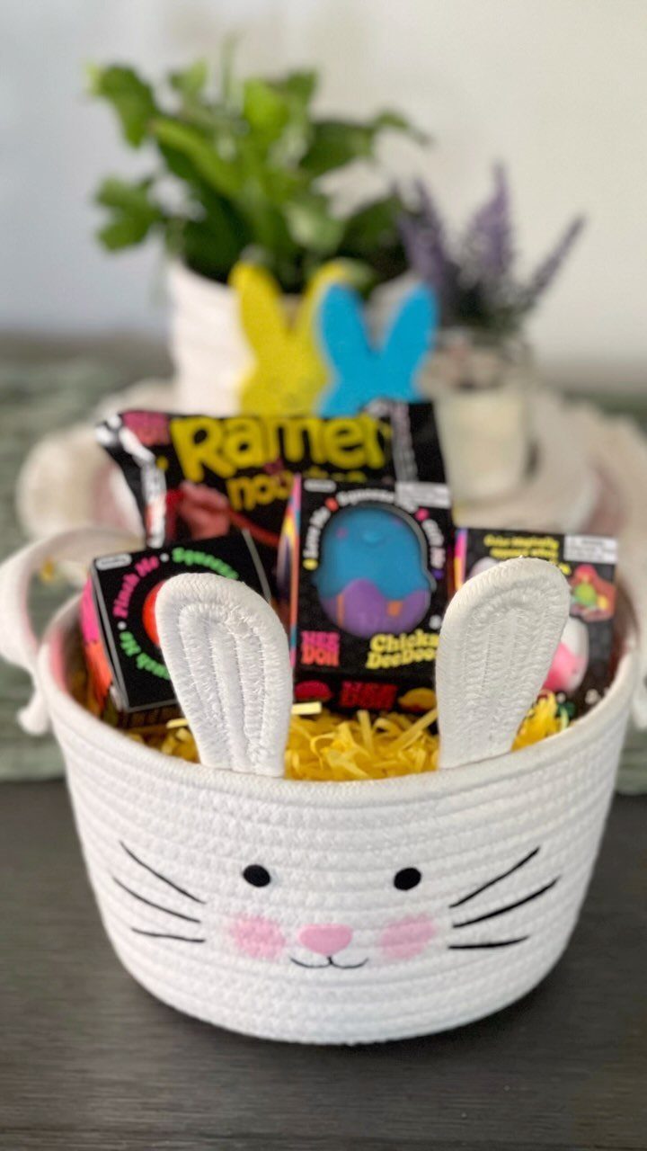 White crocheted bunny basket filled with yellow grass and various non-candy toys.