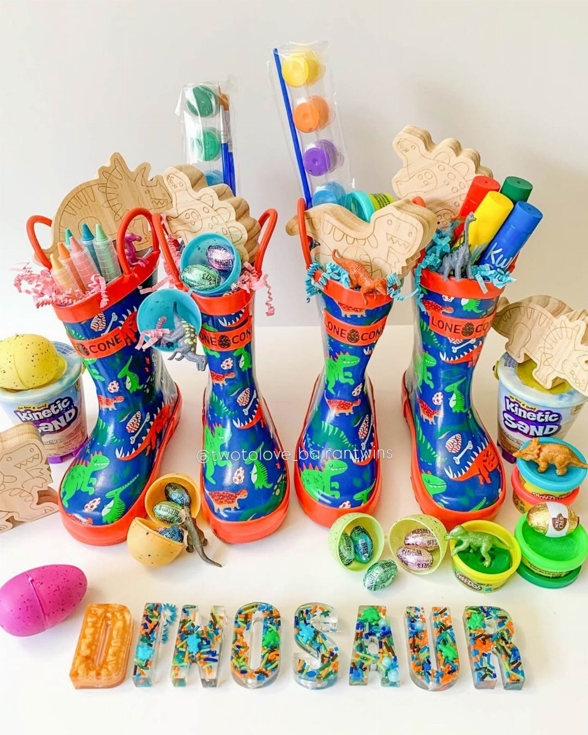 Blue dinosaur rain boots filled with Easter treats and toys on white background