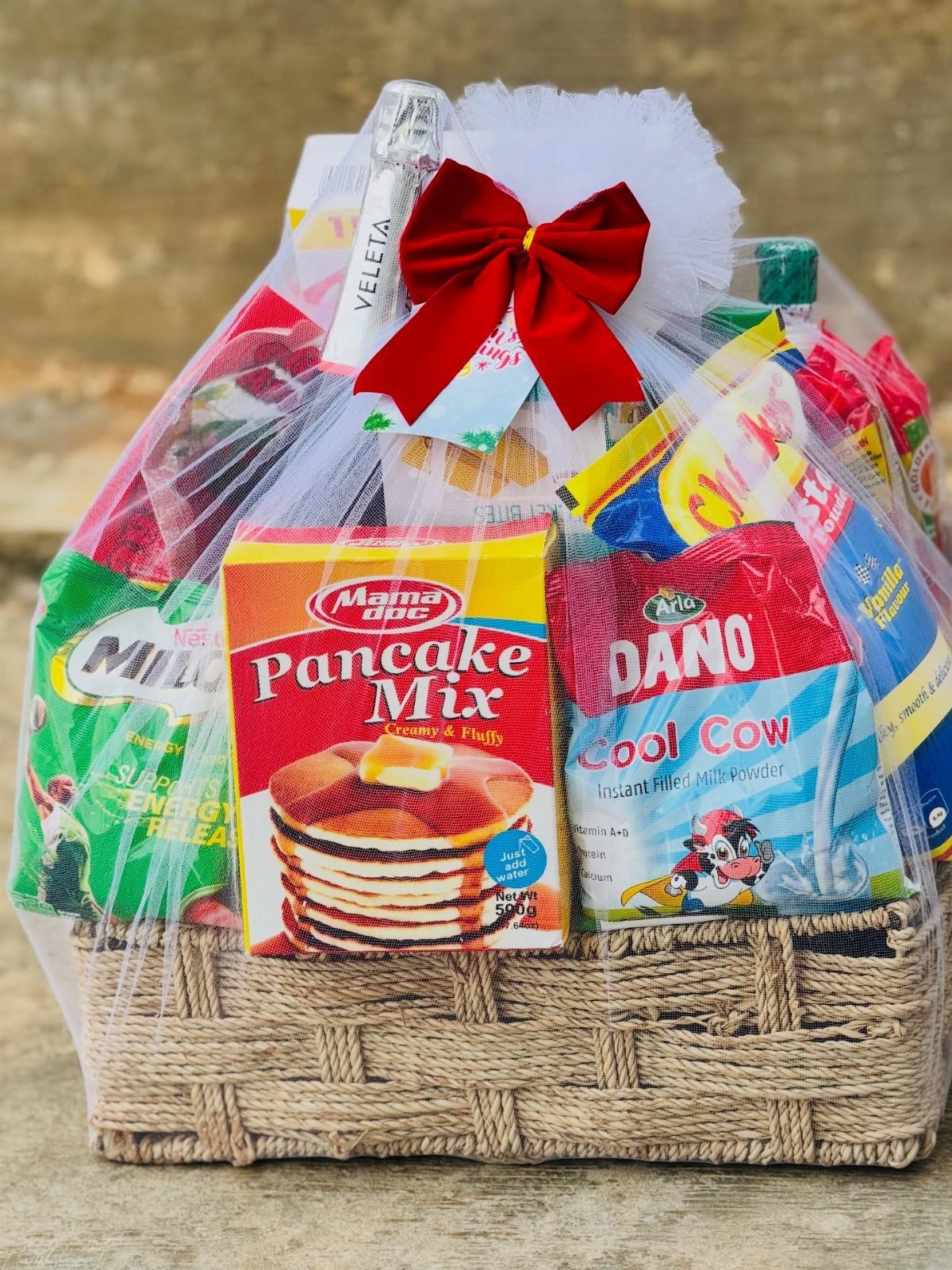 Woven gift basket filled with pancake mix and breakfast items wrapped in cellophane.