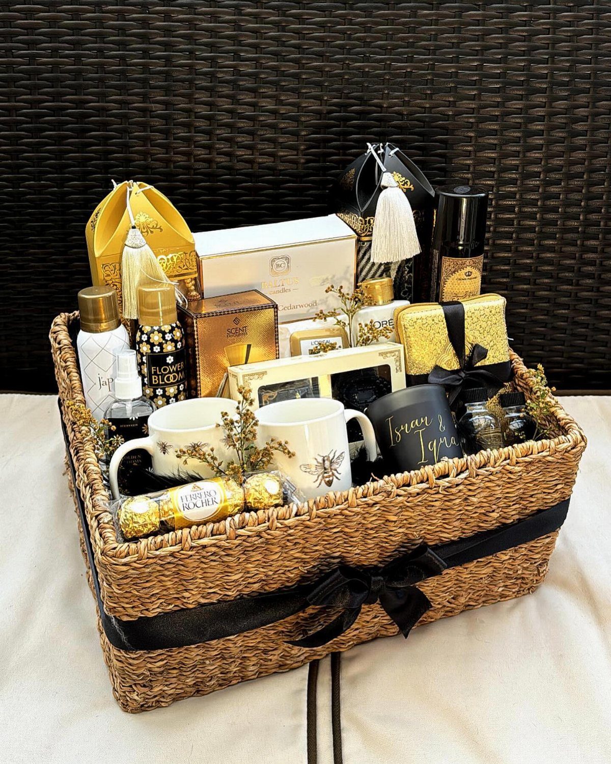 Woven gift basket filled with gold and white luxury spa and gourmet items.