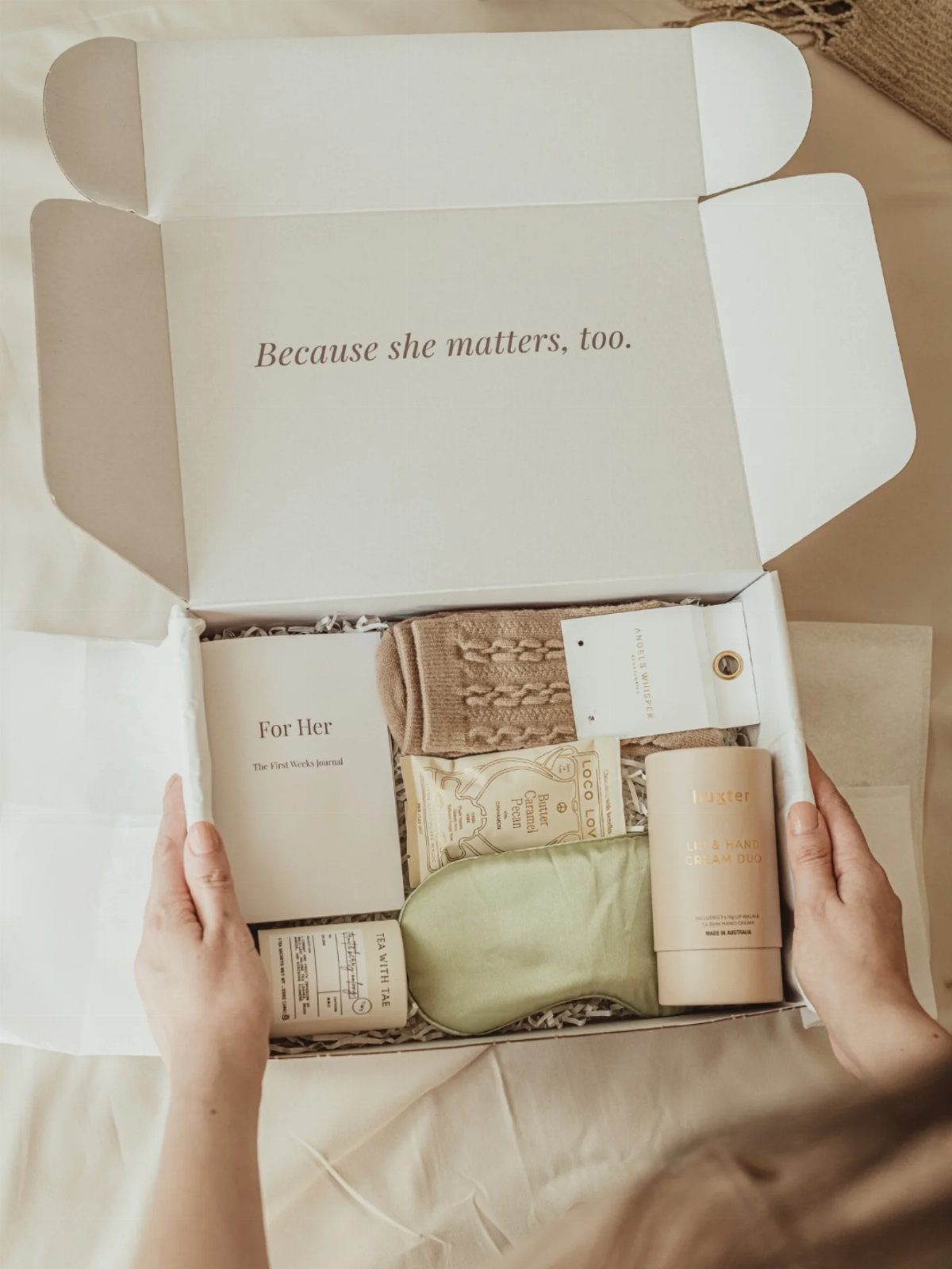 Gift box containing a green sleep mask, candle, and socks for a new mother.