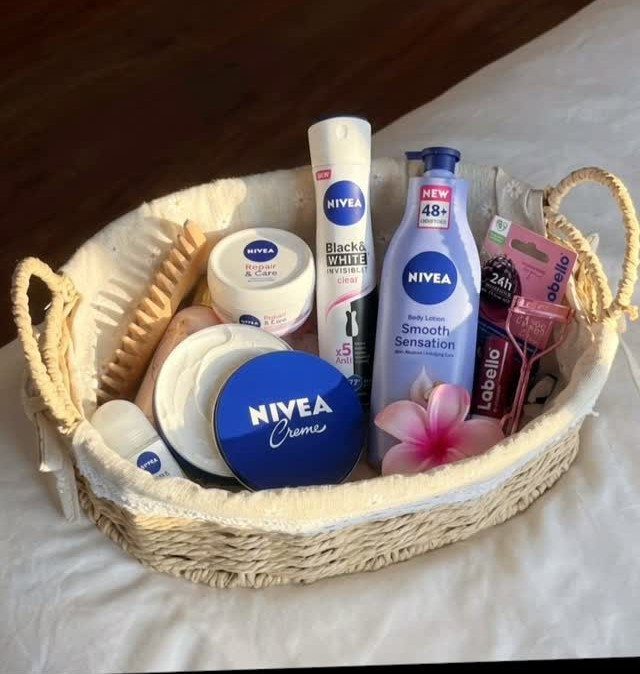 Woven gift basket filled with Nivea skincare products and a pink flower.