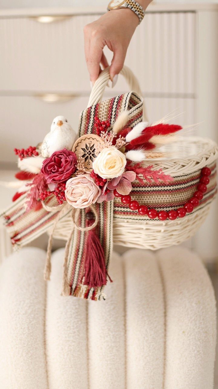 White wicker basket decorated with red ribbons, artificial flowers, and a small bird.