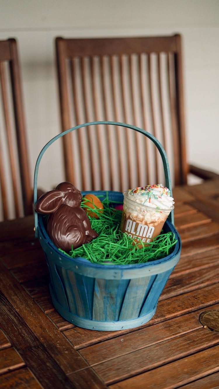Blue wooden Easter basket with a chocolate bunny and an iced coffee drink.