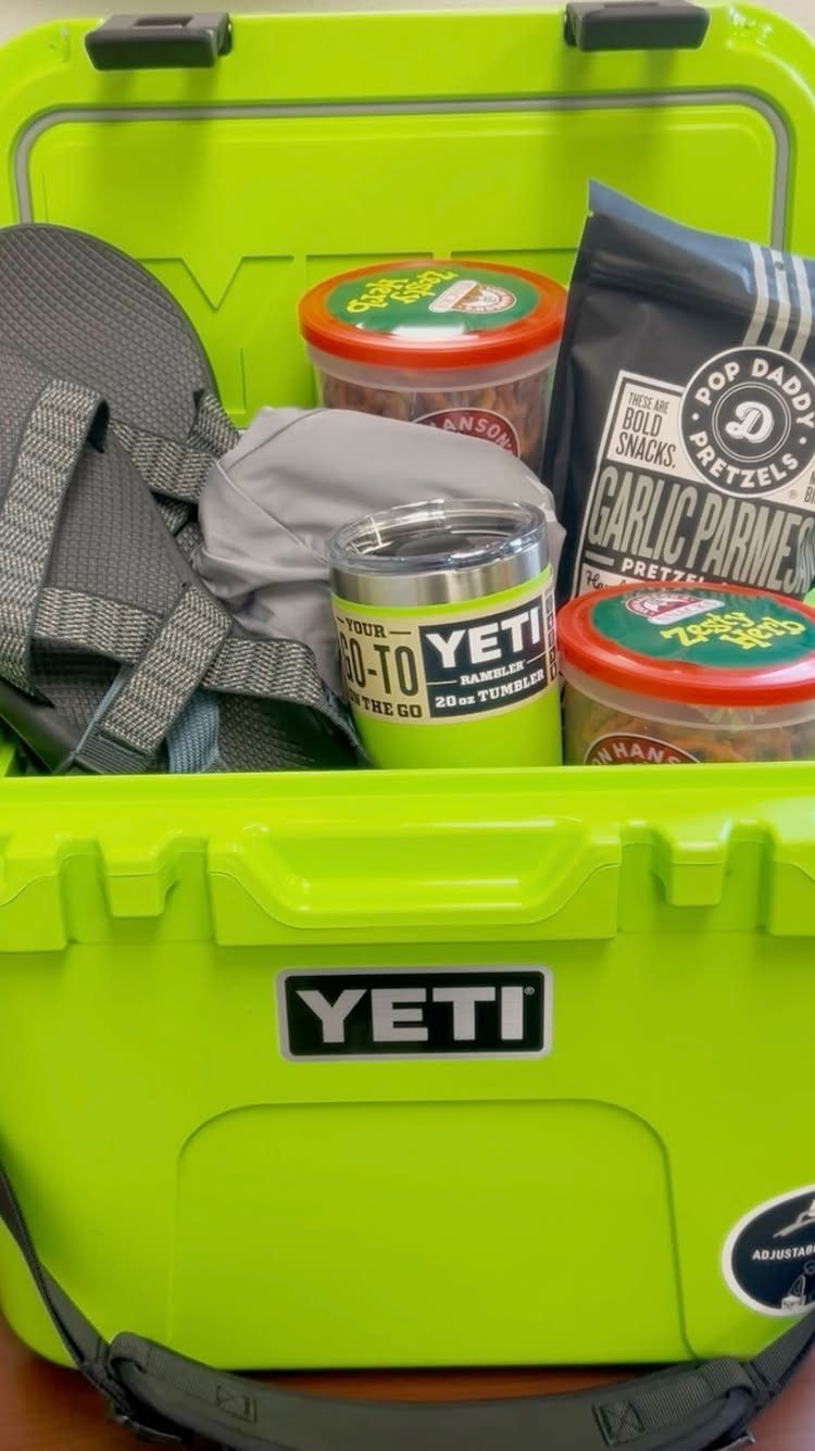 Lime green Yeti cooler filled with snacks, a tumbler, and a grey sandal.