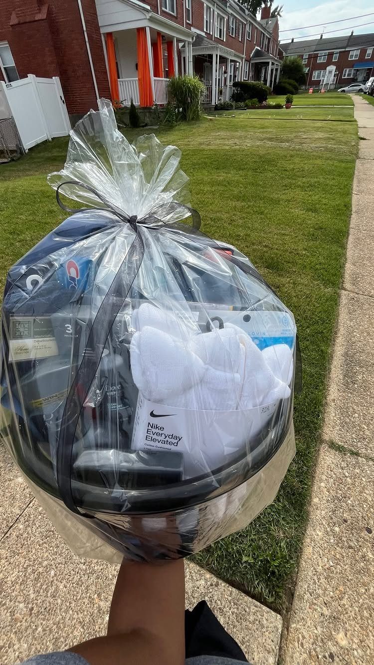 Gift basket wrapped in cellophane containing white Nike towels and other items.