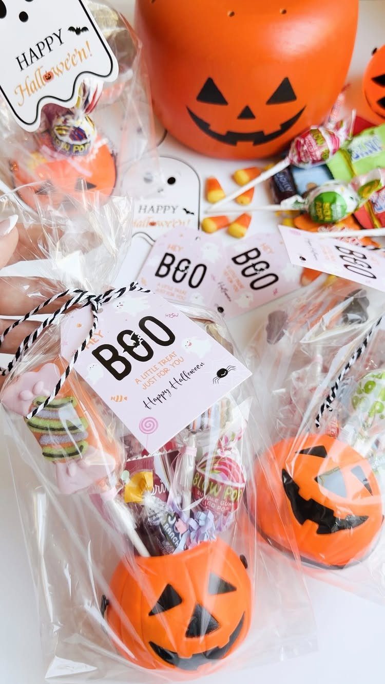 Halloween gift bags with orange pumpkin containers filled with colorful assorted candies.