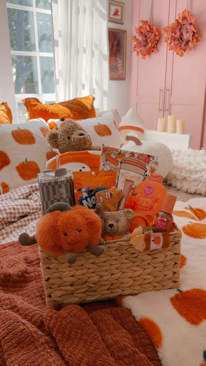 Woven gift basket filled with orange snacks and plushies on pumpkin bedding