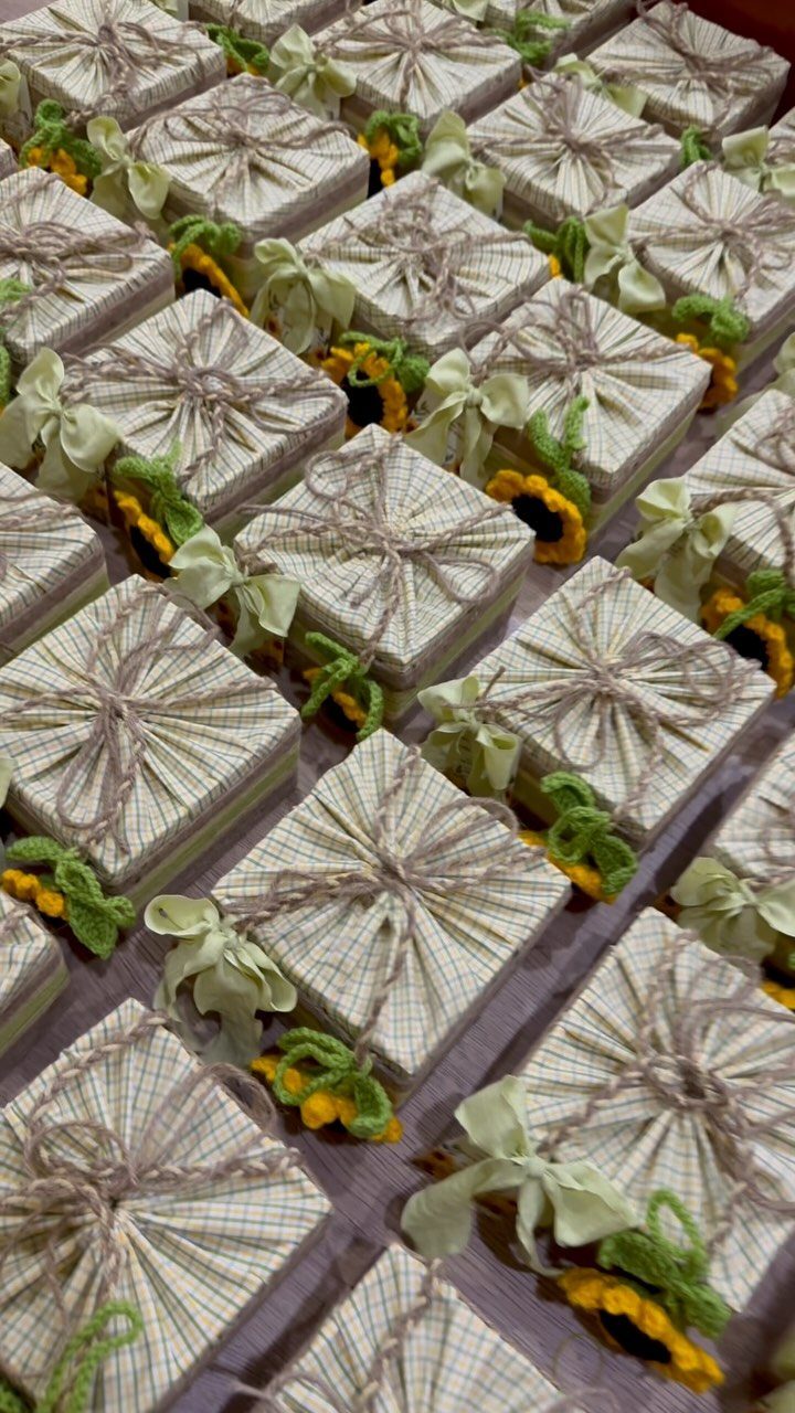 Small square gift boxes wrapped in twine and decorated with yellow sunflowers.