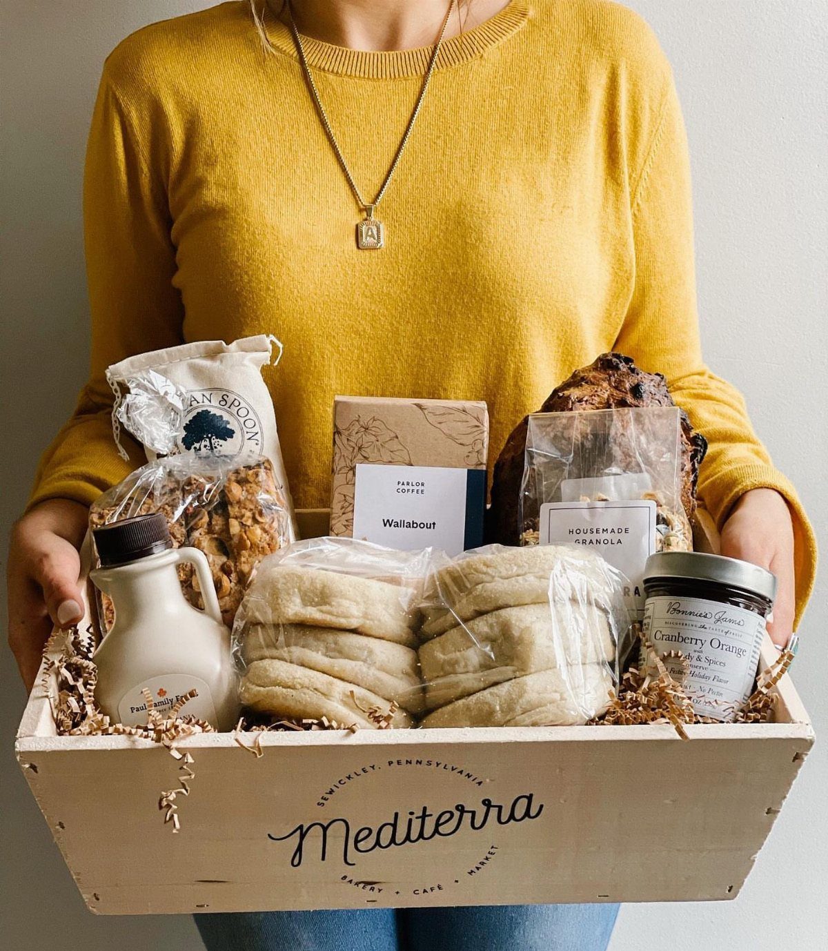Breakfast gift basket in a wooden crate containing bagels, granola, and spreads.