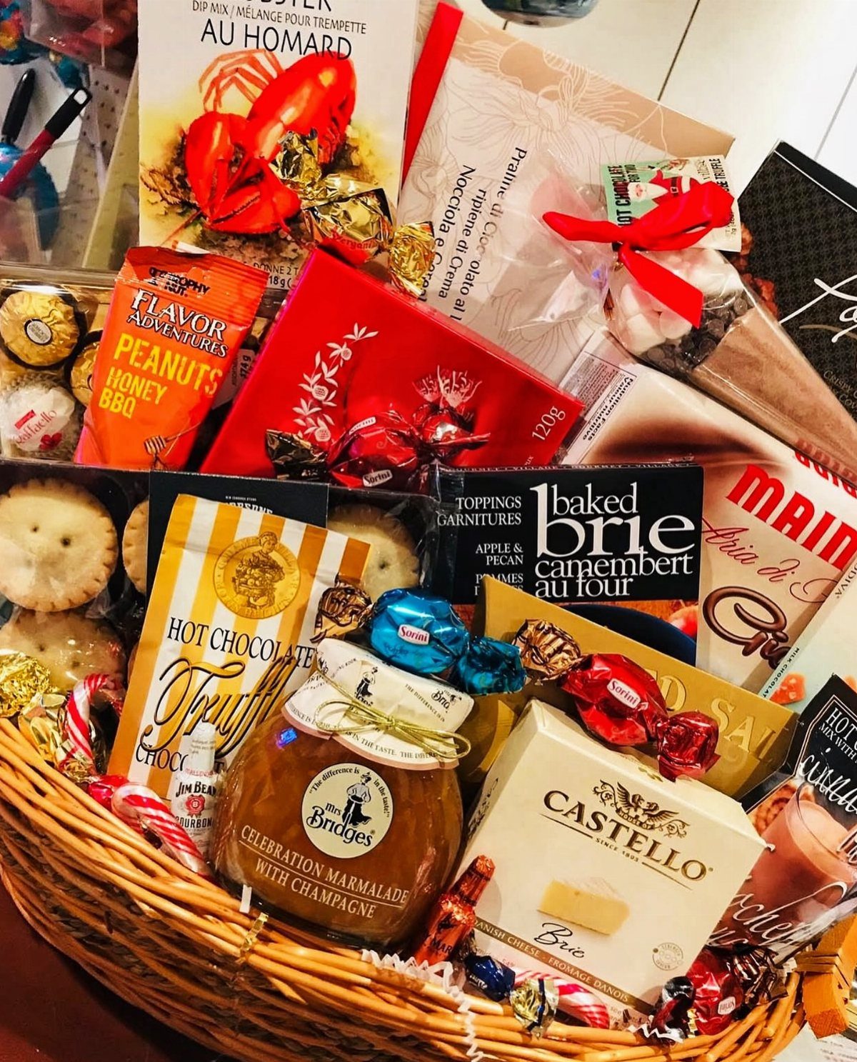 Wicker gift basket filled with gourmet cheese, marmalade, chocolates, and a lobster cookbook.