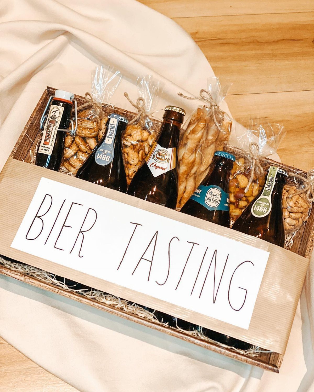 Beer tasting gift basket with brown bottles and snacks in a wooden tray