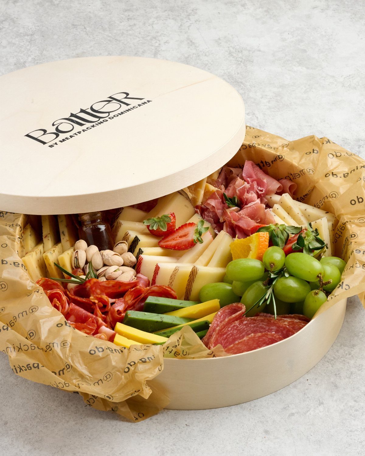 Meat and cheese gift box with grapes, strawberries, and nuts in wooden container