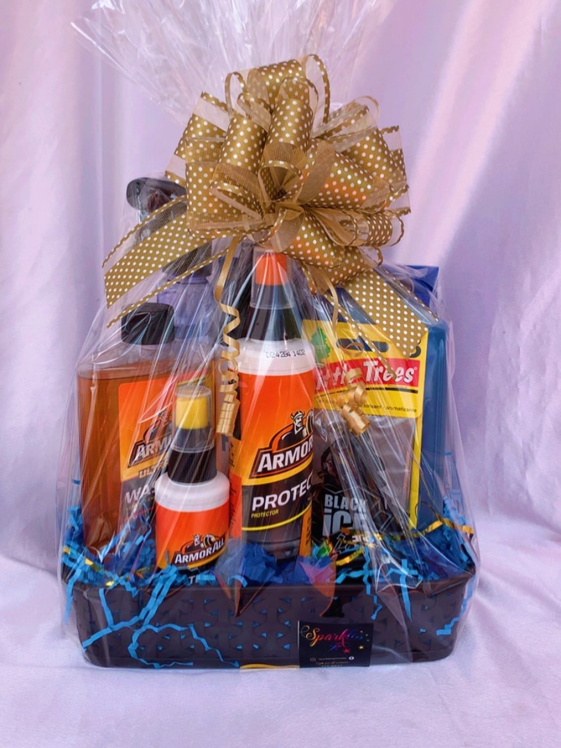 Car cleaning supplies gift basket wrapped in cellophane with a gold polka-dot bow.