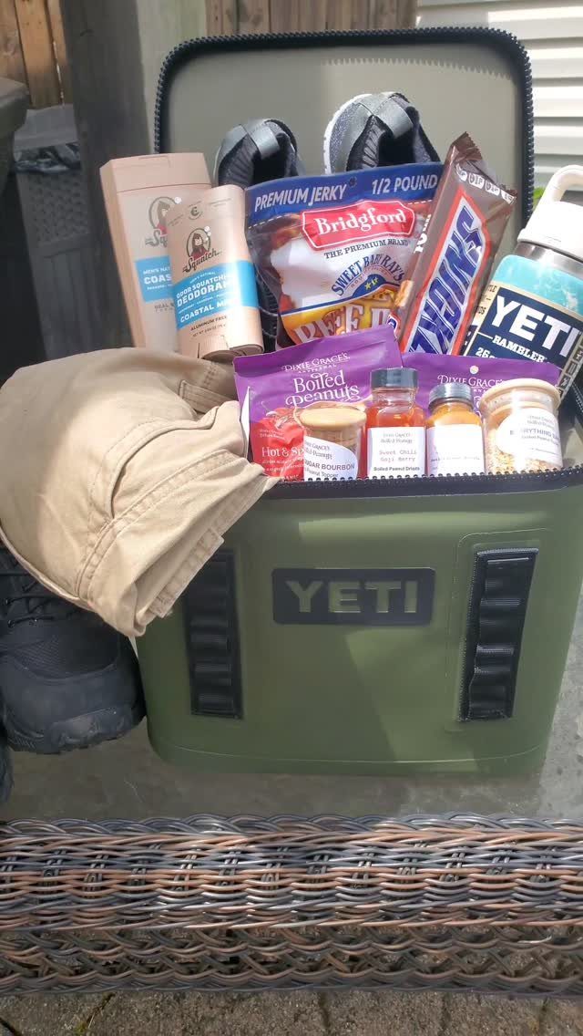 Olive green Yeti cooler filled with snacks, shoes, and clothing as a gift basket.