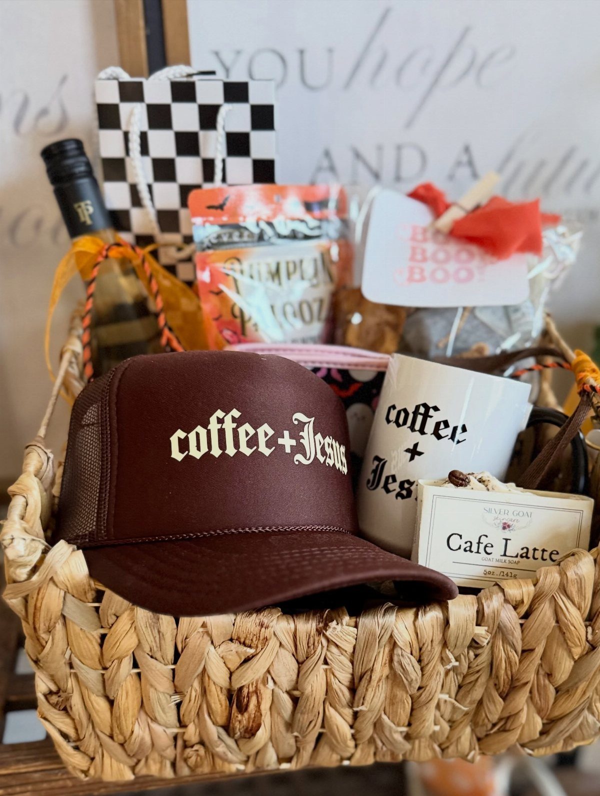 Woven gift basket containing a coffee-themed hat, mug, and latte treats.