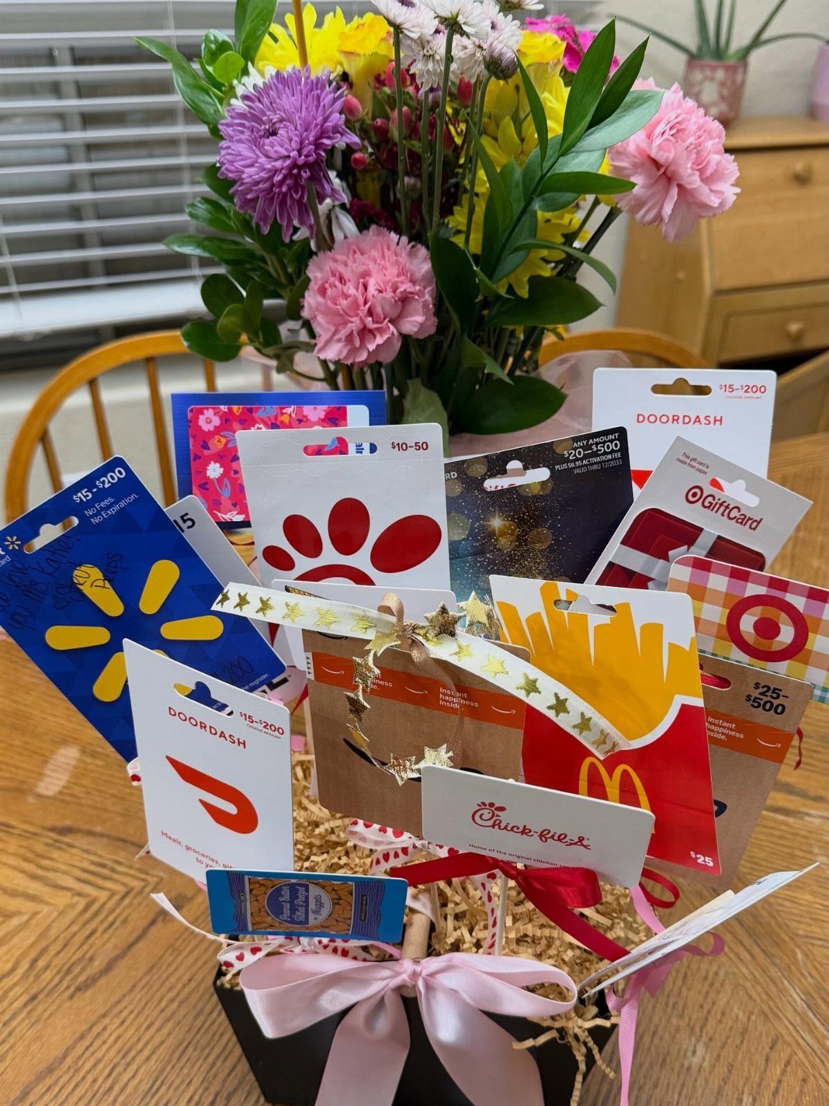 Gift basket filled with various restaurant and retail gift cards and a pink bow.