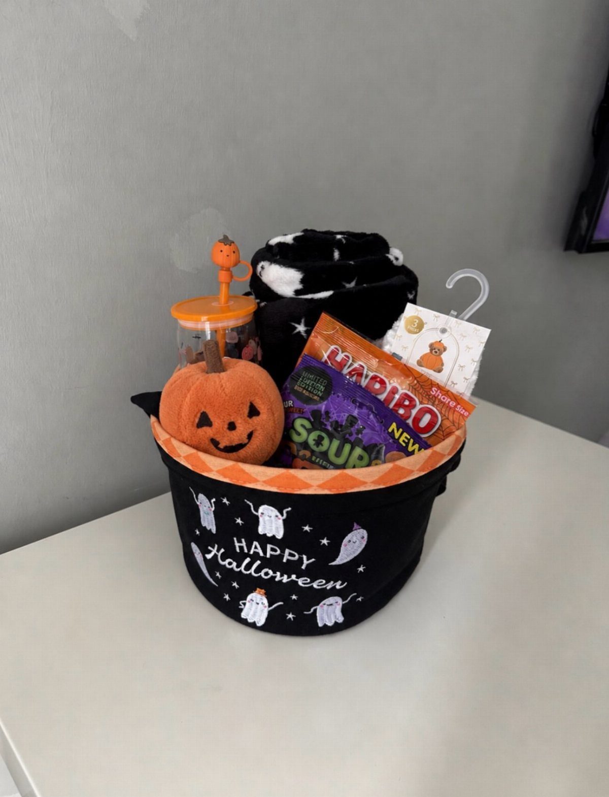 Halloween themed gift bucket filled with a plush pumpkin and sour gummy candies.