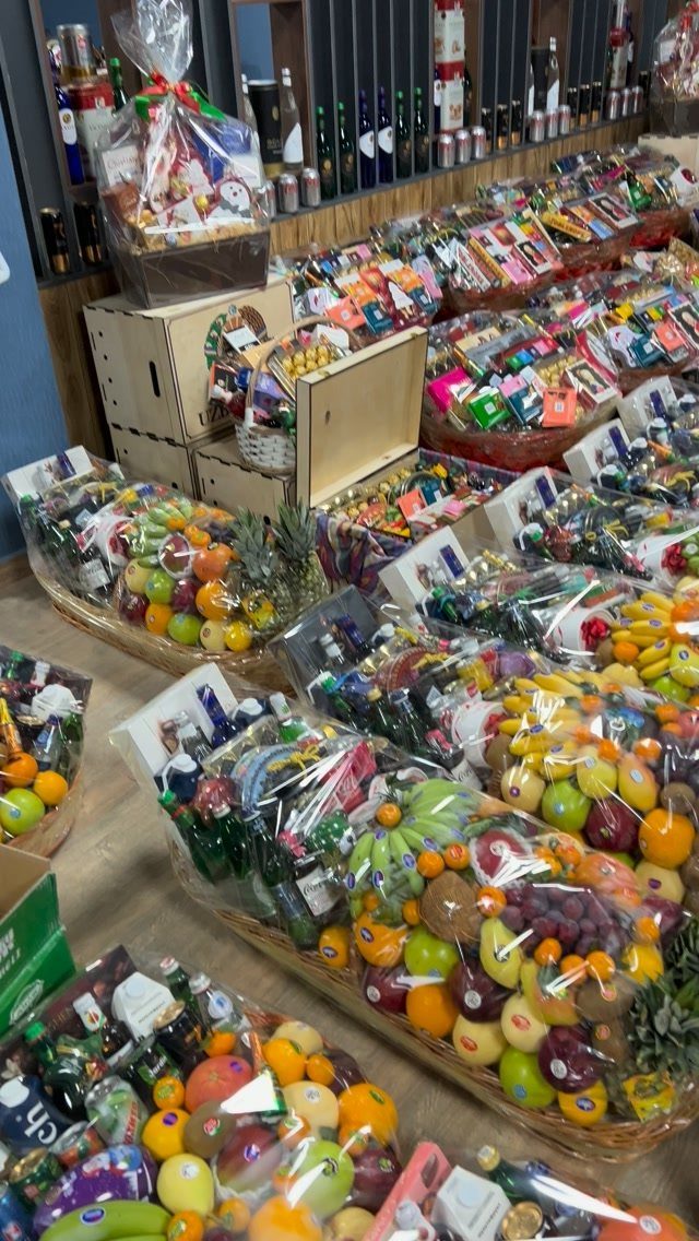 Assorted gift baskets filled with fruit and wine wrapped in clear cellophane.