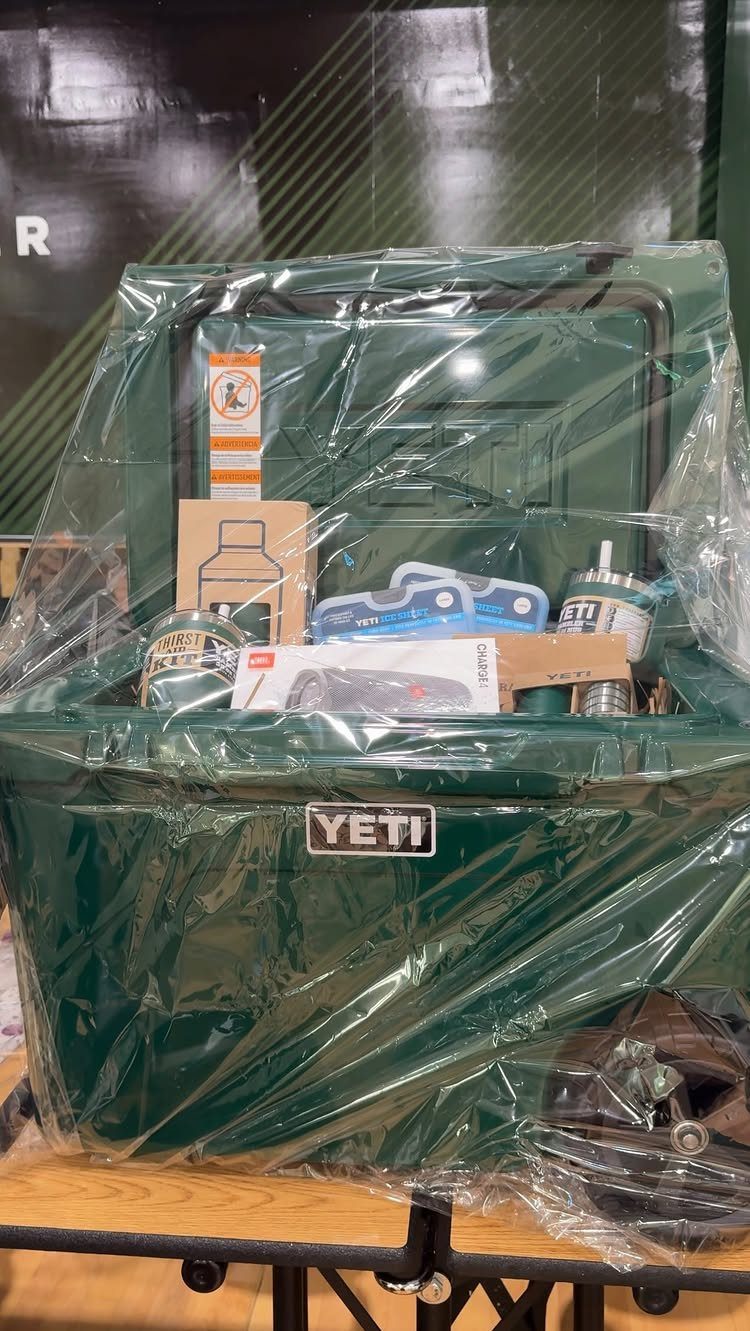 Green Yeti cooler filled with gift items and wrapped in clear cellophane plastic.