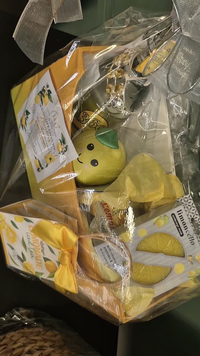 Yellow themed gift basket wrapped in cellophane with lemon snacks and plush toy.