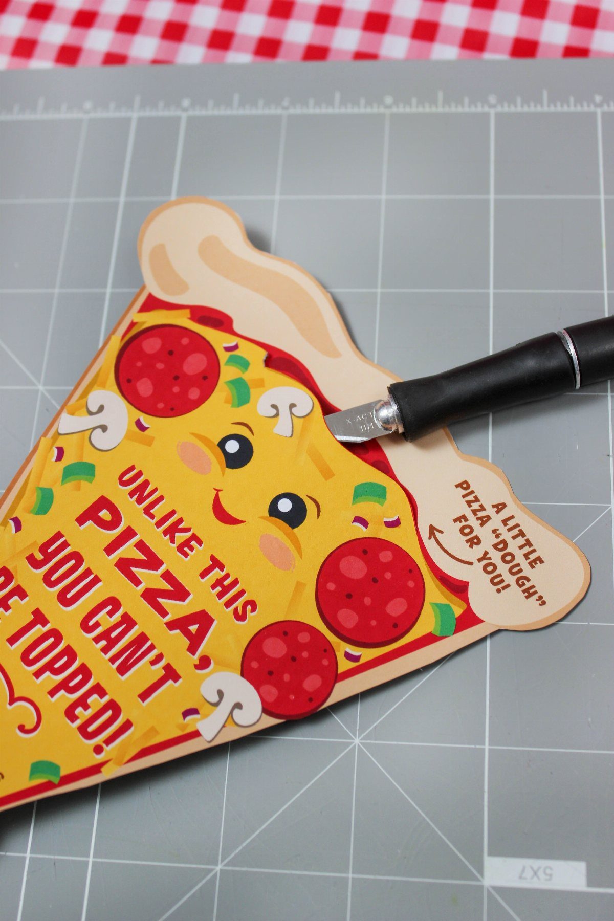 Pizza-shaped gift card holder with a cartoon character being cut by a craft knife.