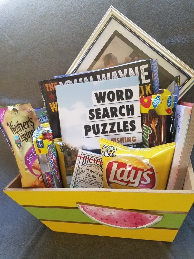 Word search puzzle book and snacks inside a yellow watermelon themed wooden tray.