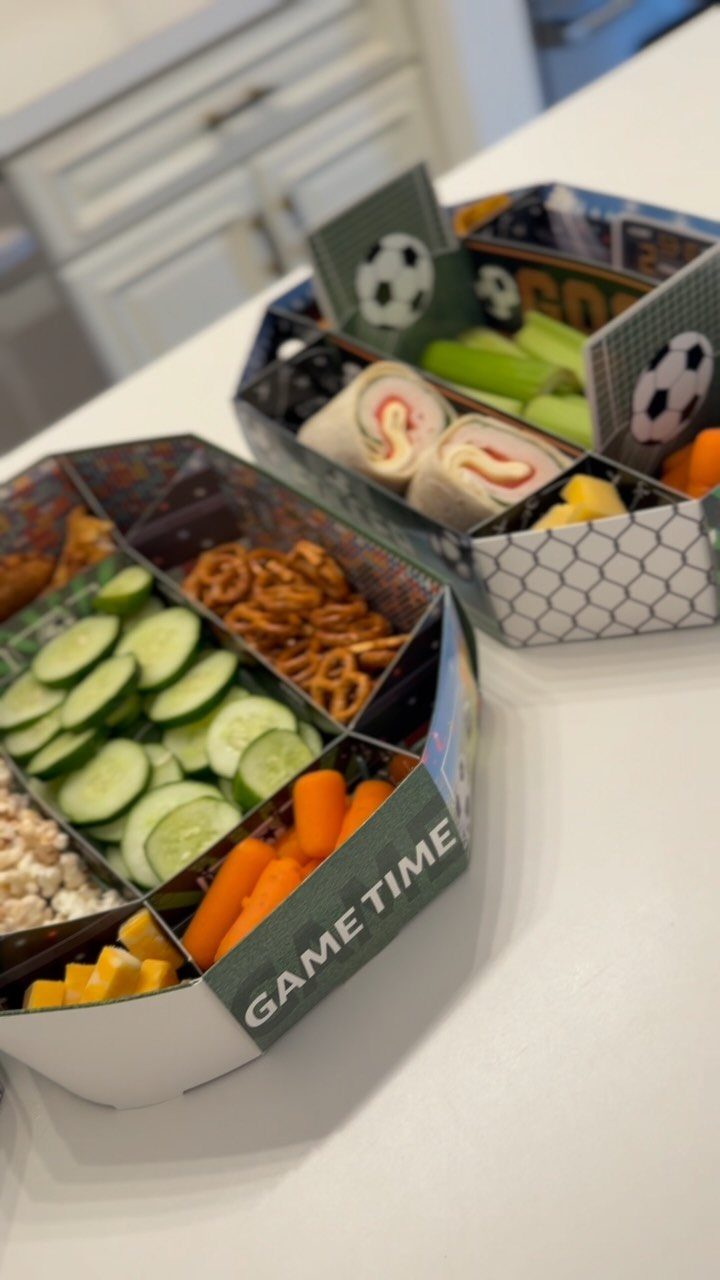 Two partitioned snack trays filled with vegetables and pretzels for game time.
