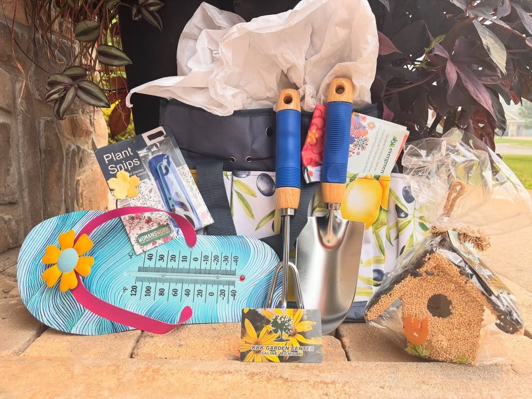 Gardening kit with hand tools, plant snips, and a birdhouse on stone pavement.
