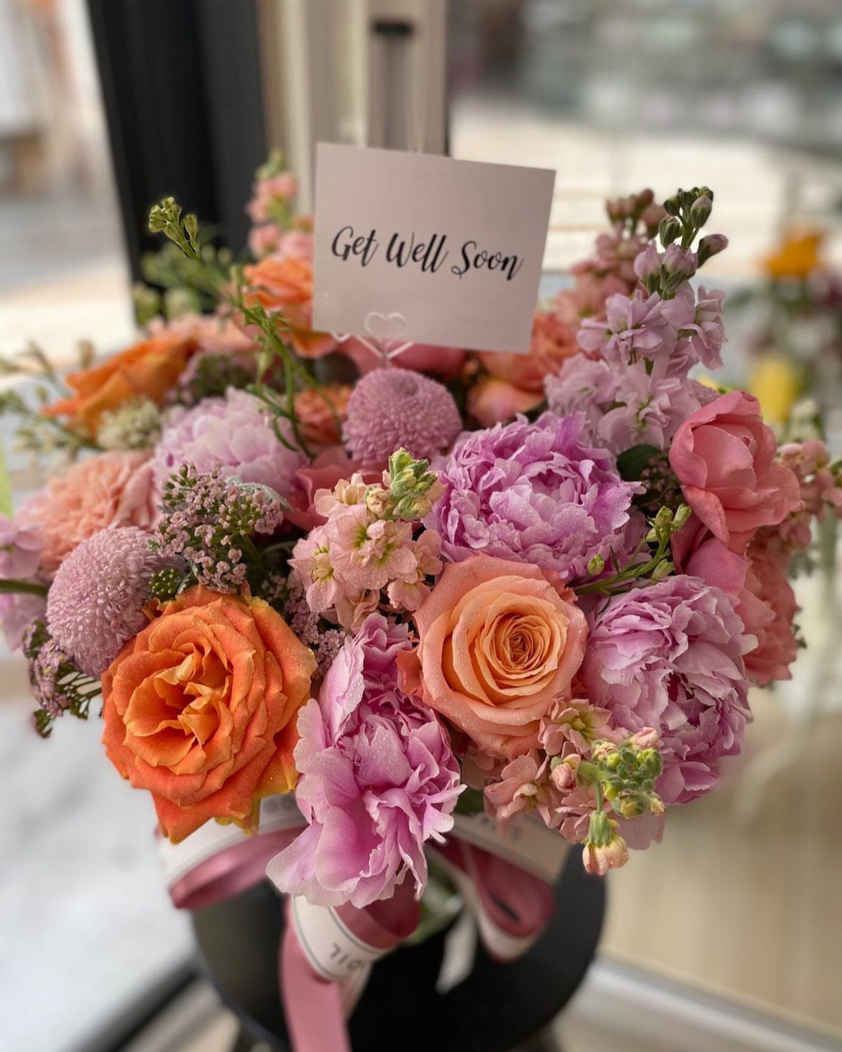 Bouquet of pink and orange flowers with a Get Well Soon card.