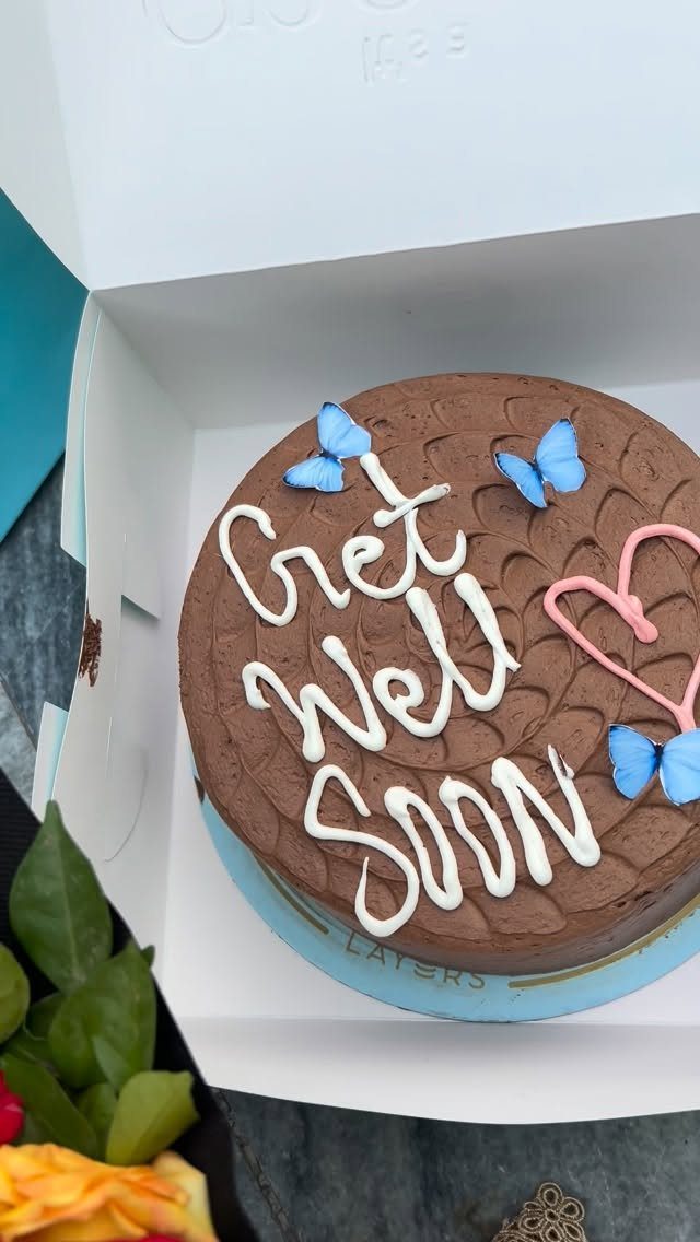 Chocolate cake with white frosting saying Get Well Soon and blue butterfly decorations