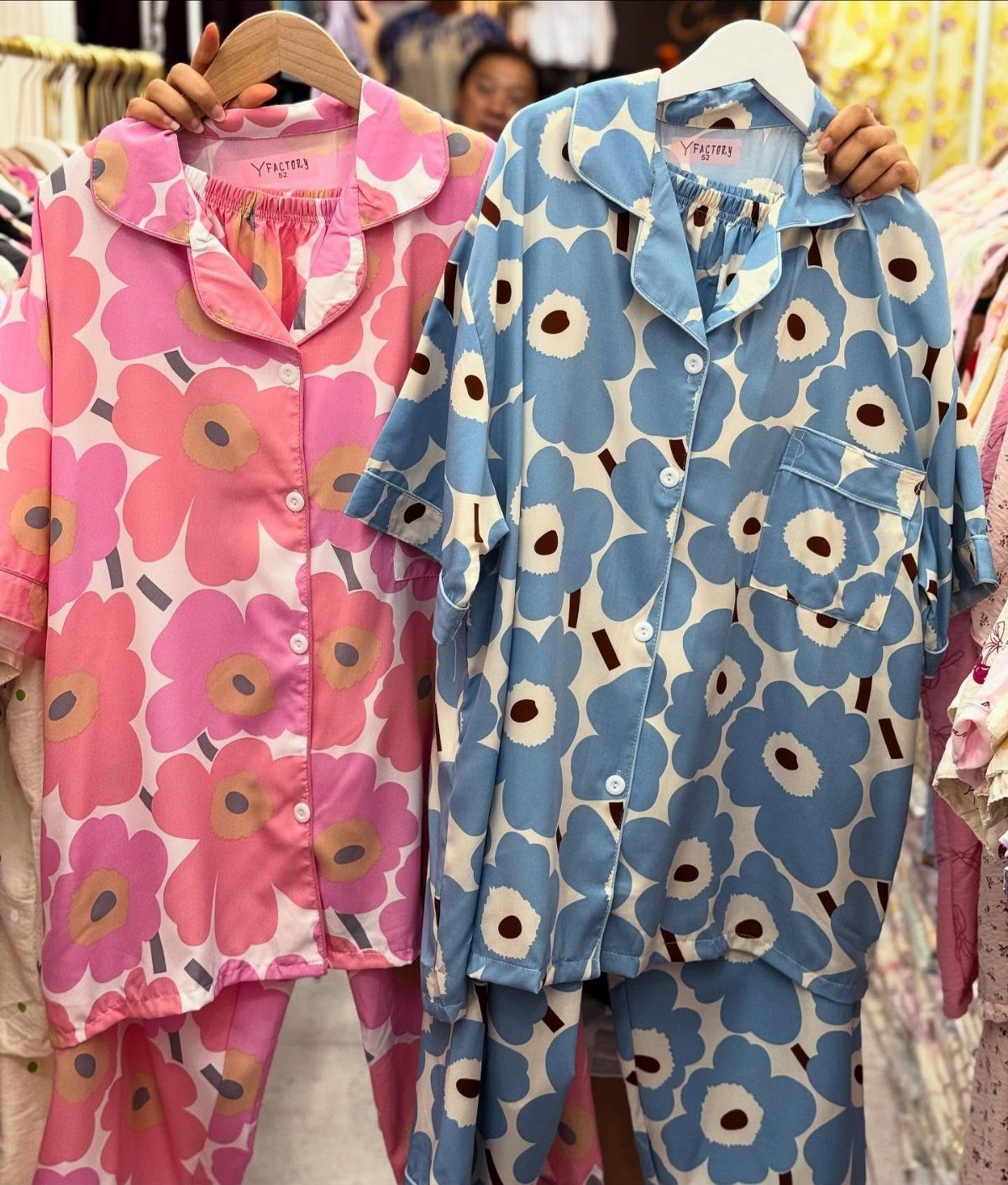 Pink and blue floral satin pajama sets hanging on hangers in a store.